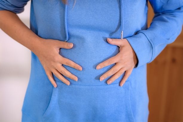 A woman holding her stomach while bloated