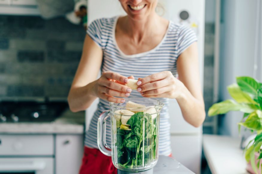 A woman making a smoothie in her kitchen.